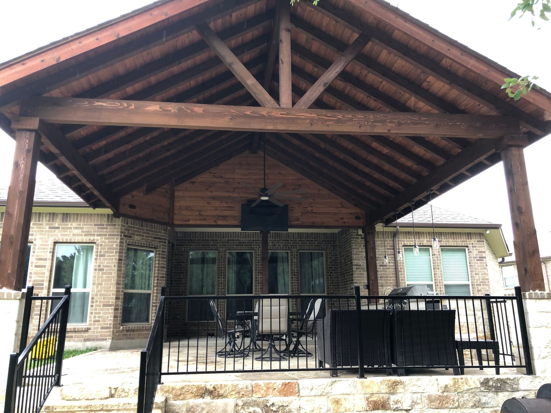 A brick house with a wooden porch and stairs built by Fine Patio Design San Antonio TX