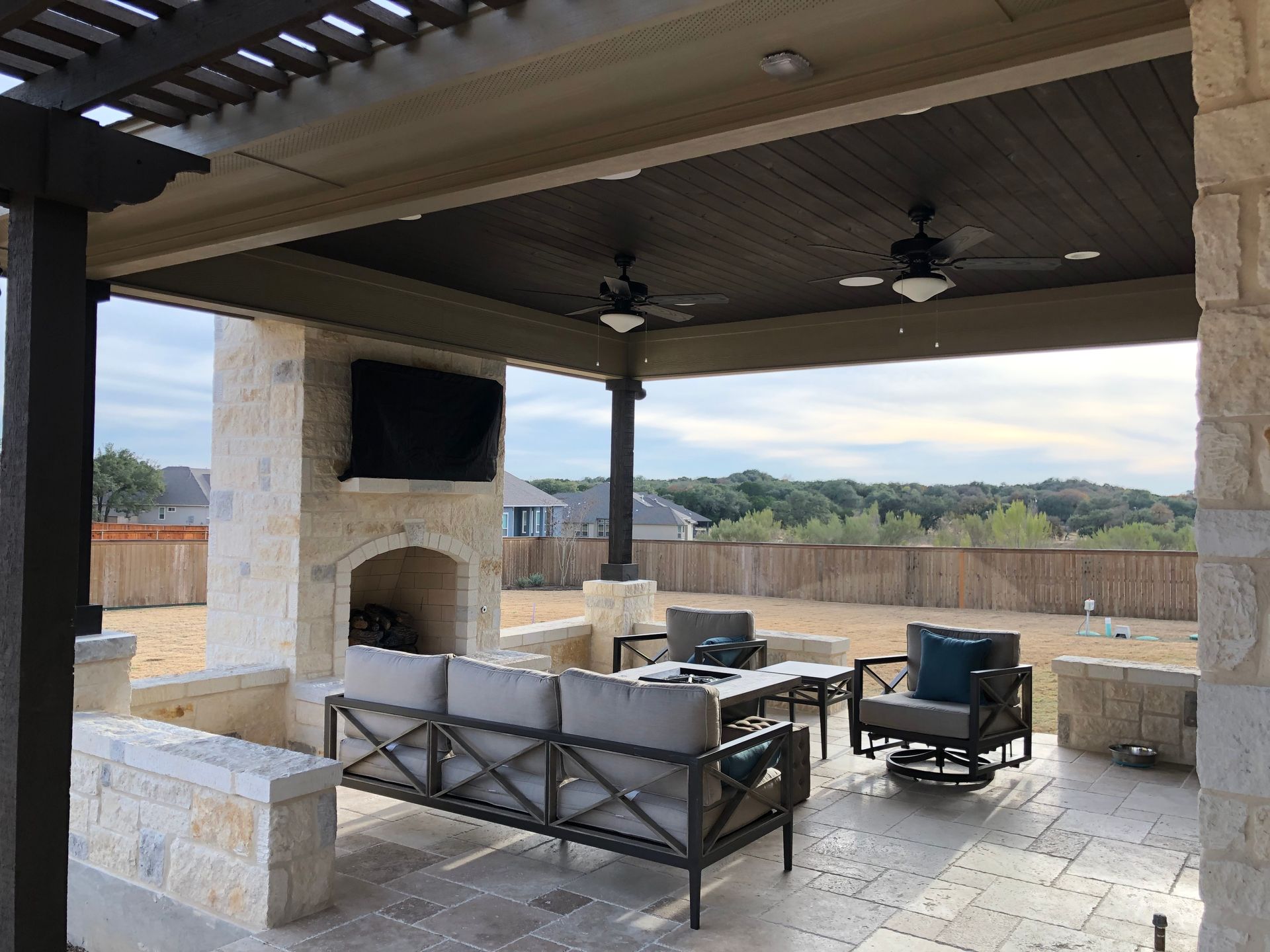 A patio with a couch and chairs under a pergola built by Fine Patio Design San Antonio TX