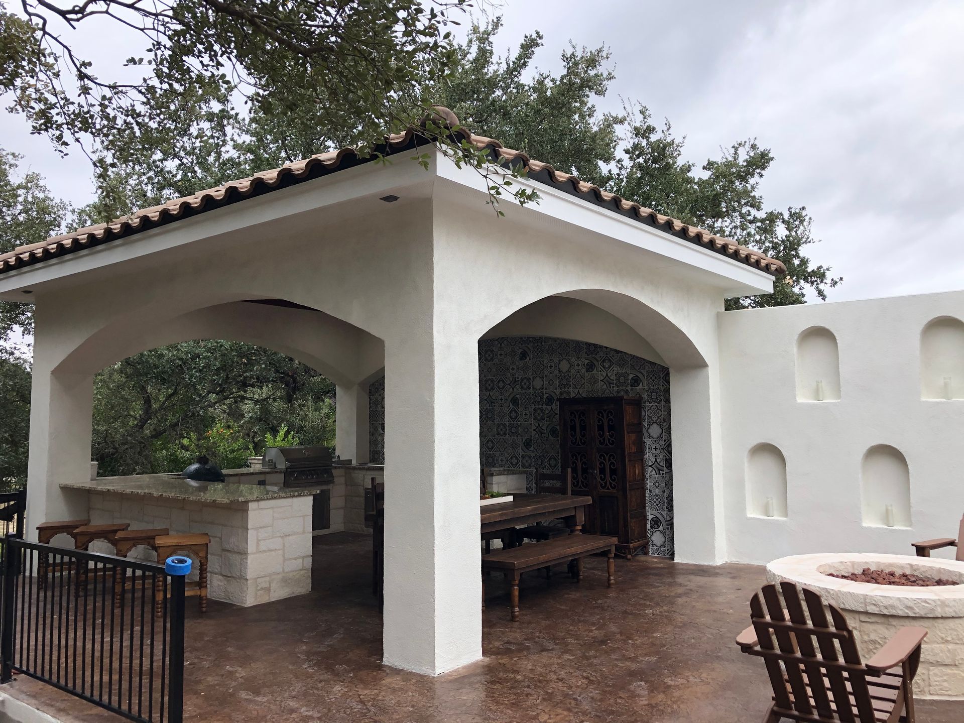 A white building with arches and a fire pit built by Fine Patio Design San Antonio TX