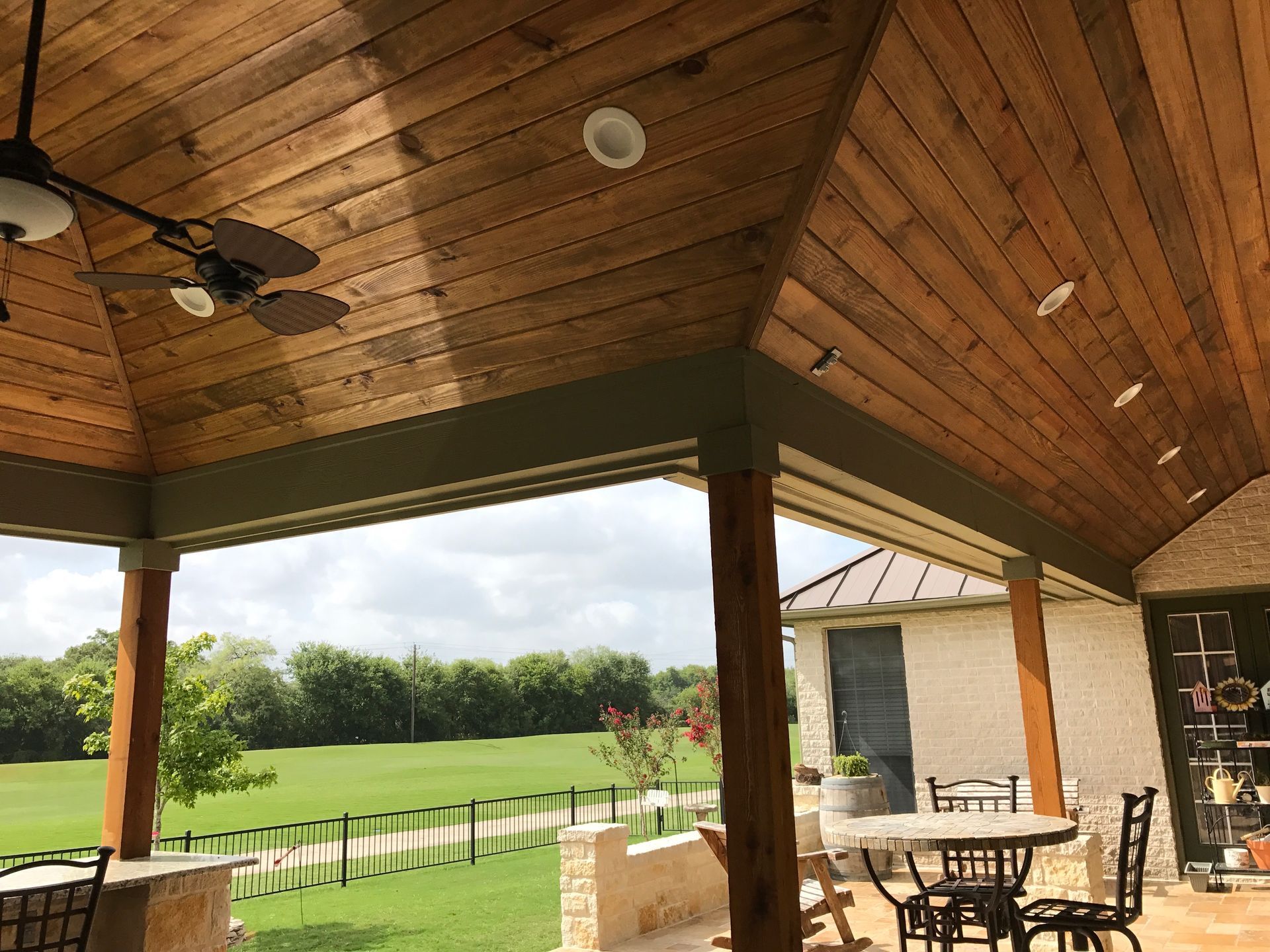 A patio with tables and chairs and a ceiling fan built by Fine Patio Design San Antonio TX