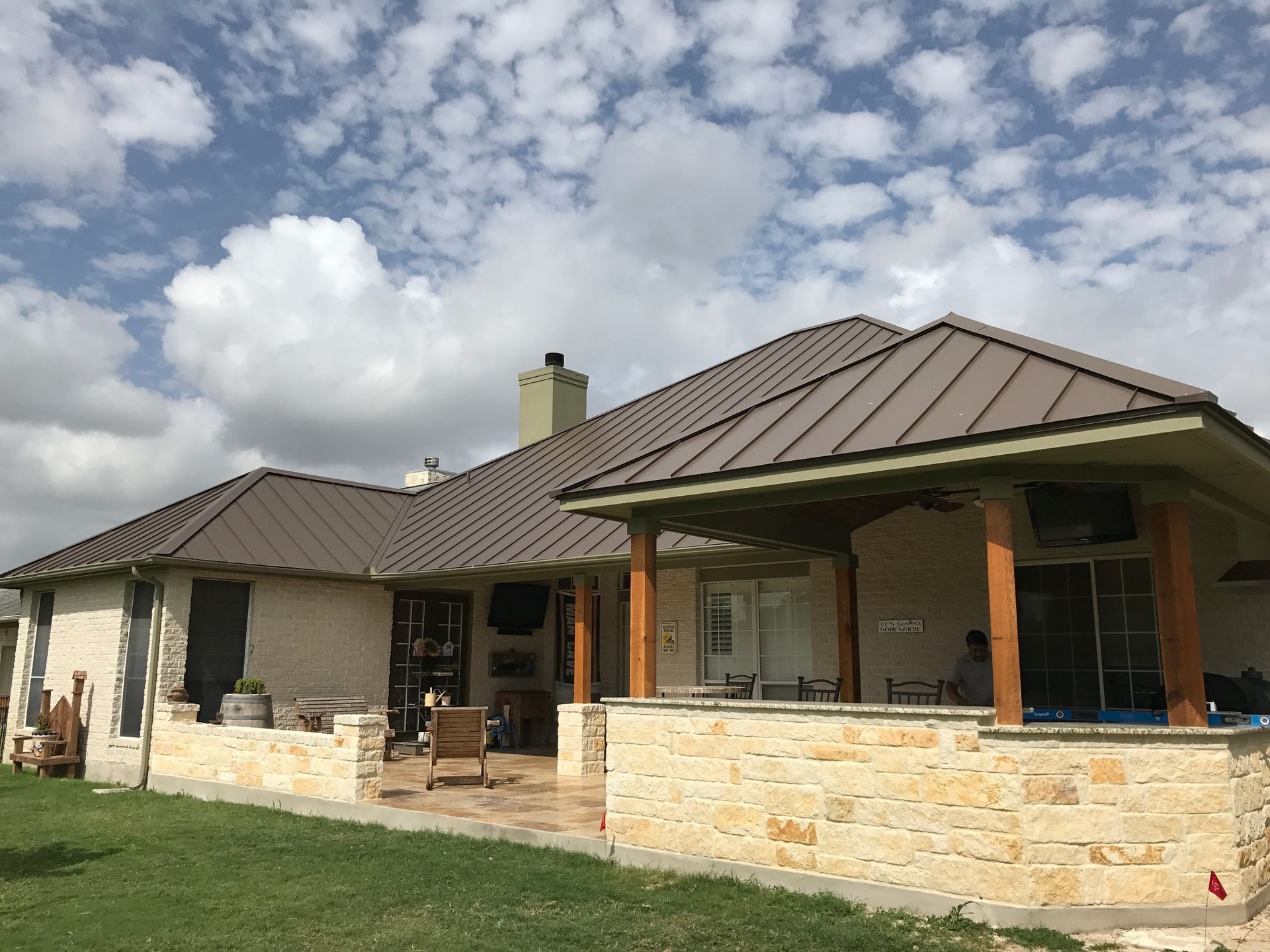A house with a metal roof and a stone wall built by Fine Patio Design San Antonio TX
