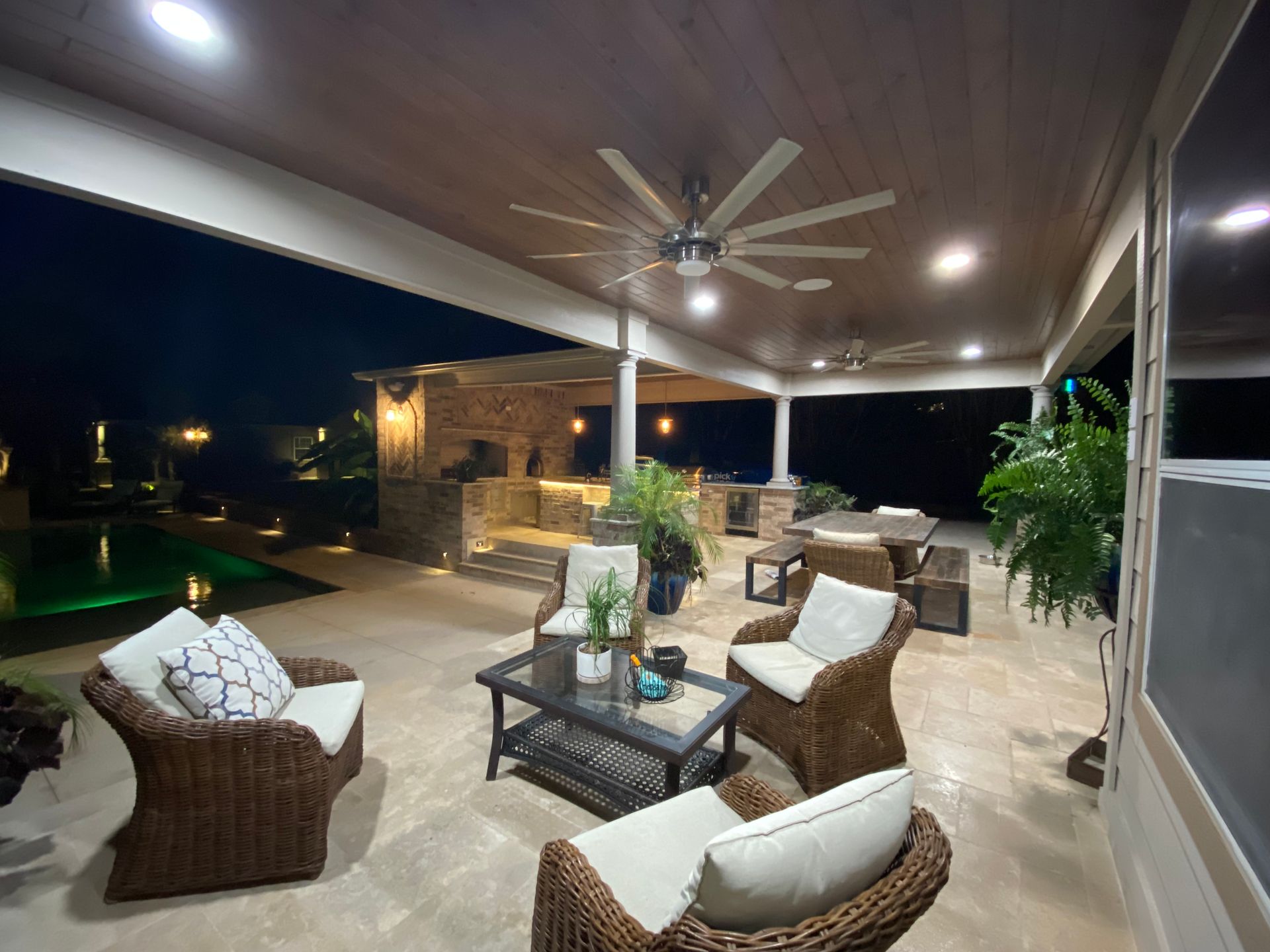 A patio with wicker furniture and a ceiling fan at night built by Fine Patio Design San Antonio TX
