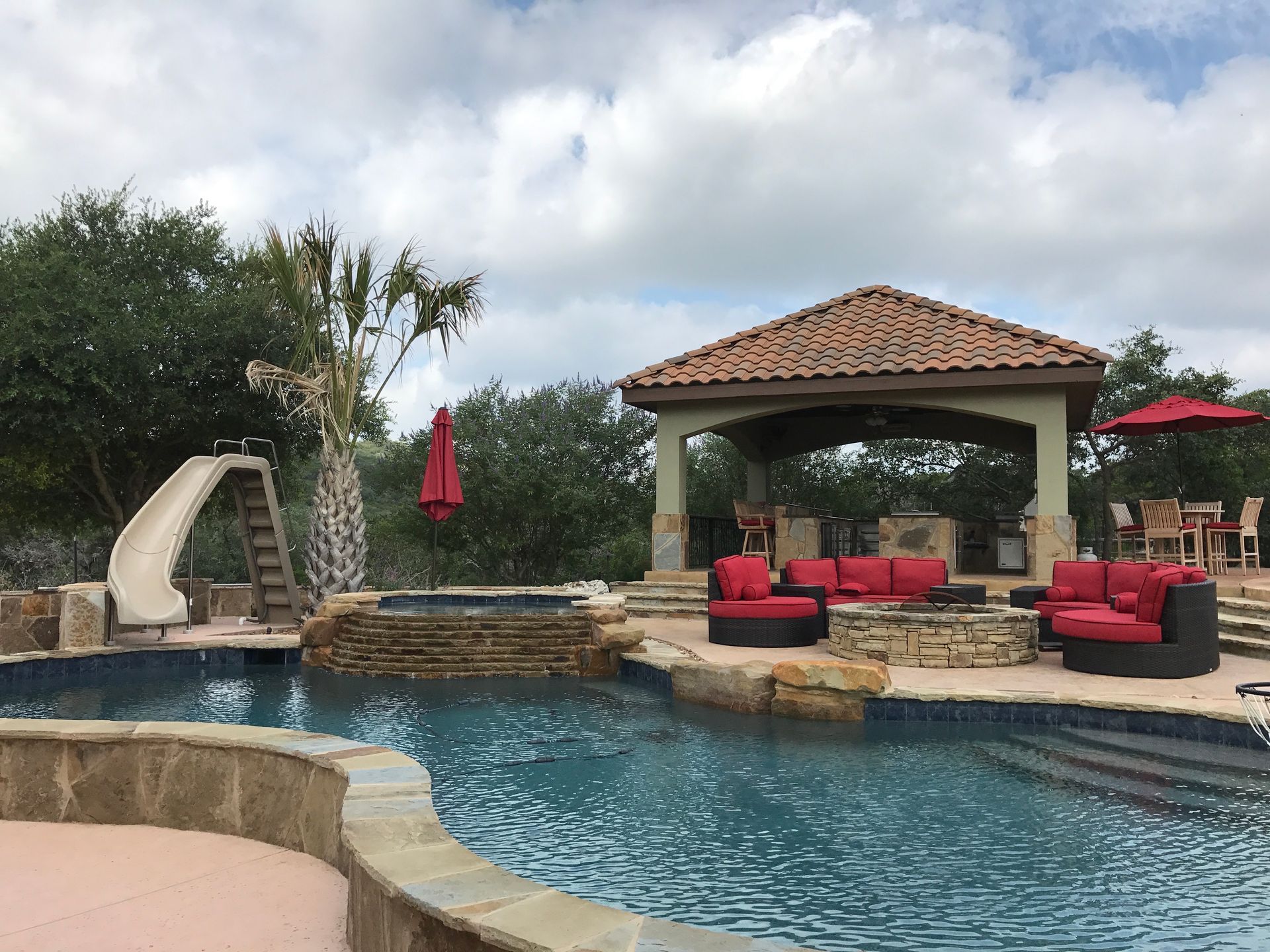 A large swimming pool with a slide and a gazebo built by Fine Patio Design San Antonio TX