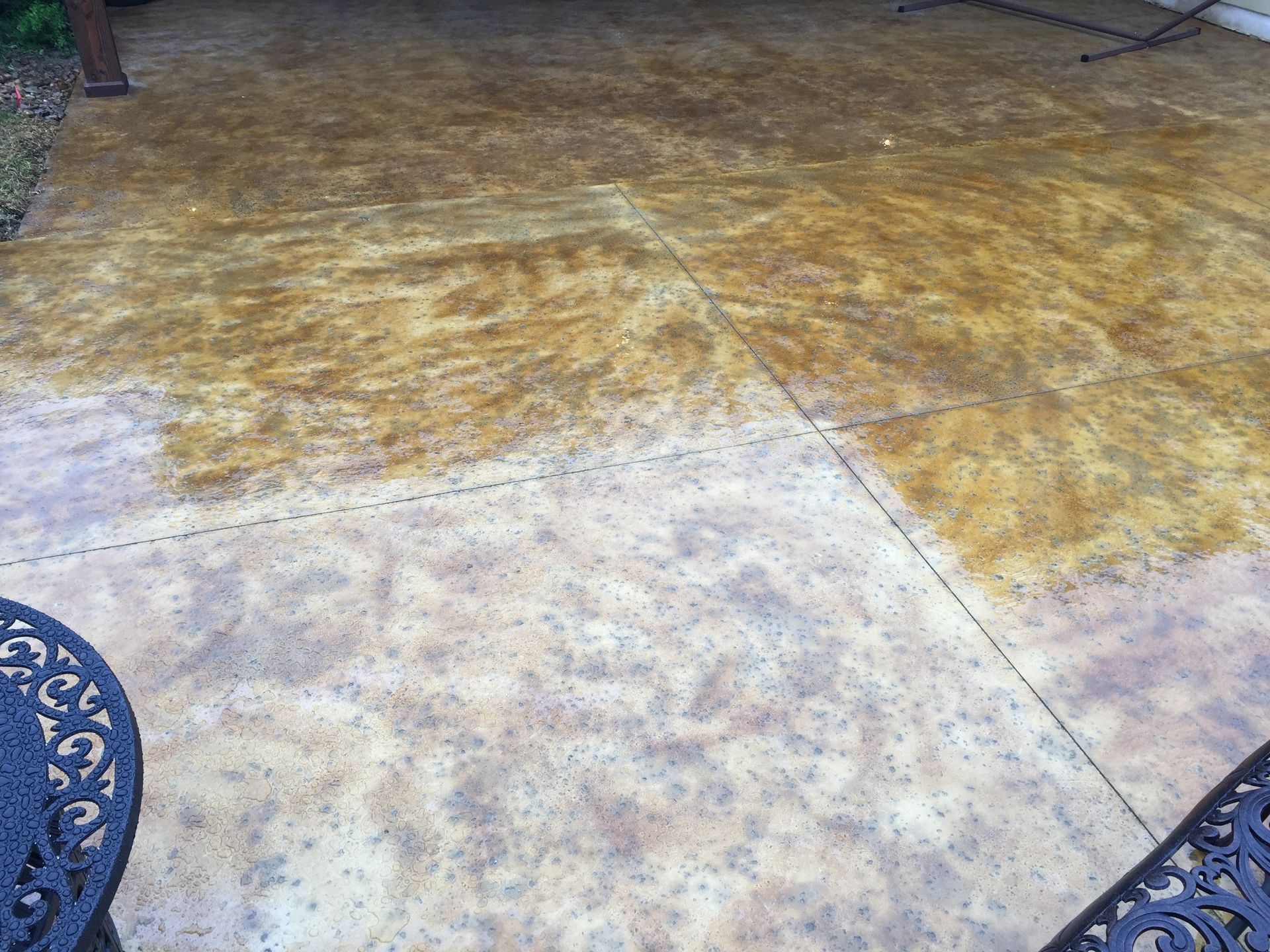 A decorative concrete patio with a chair and a table on it built by Fine Patio Design San Antonio TX