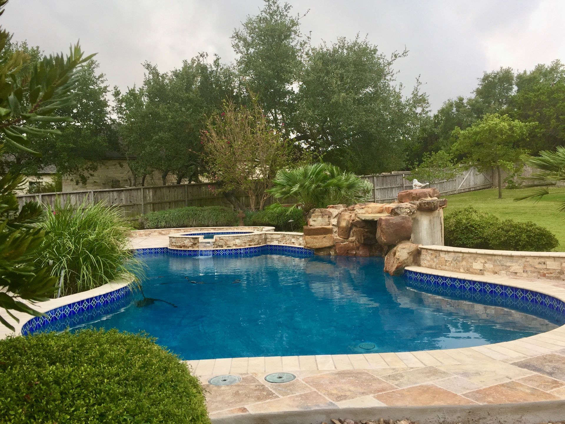A large swimming pool with a waterfall in the backyard built by Fine Patio Design San Antonio TX