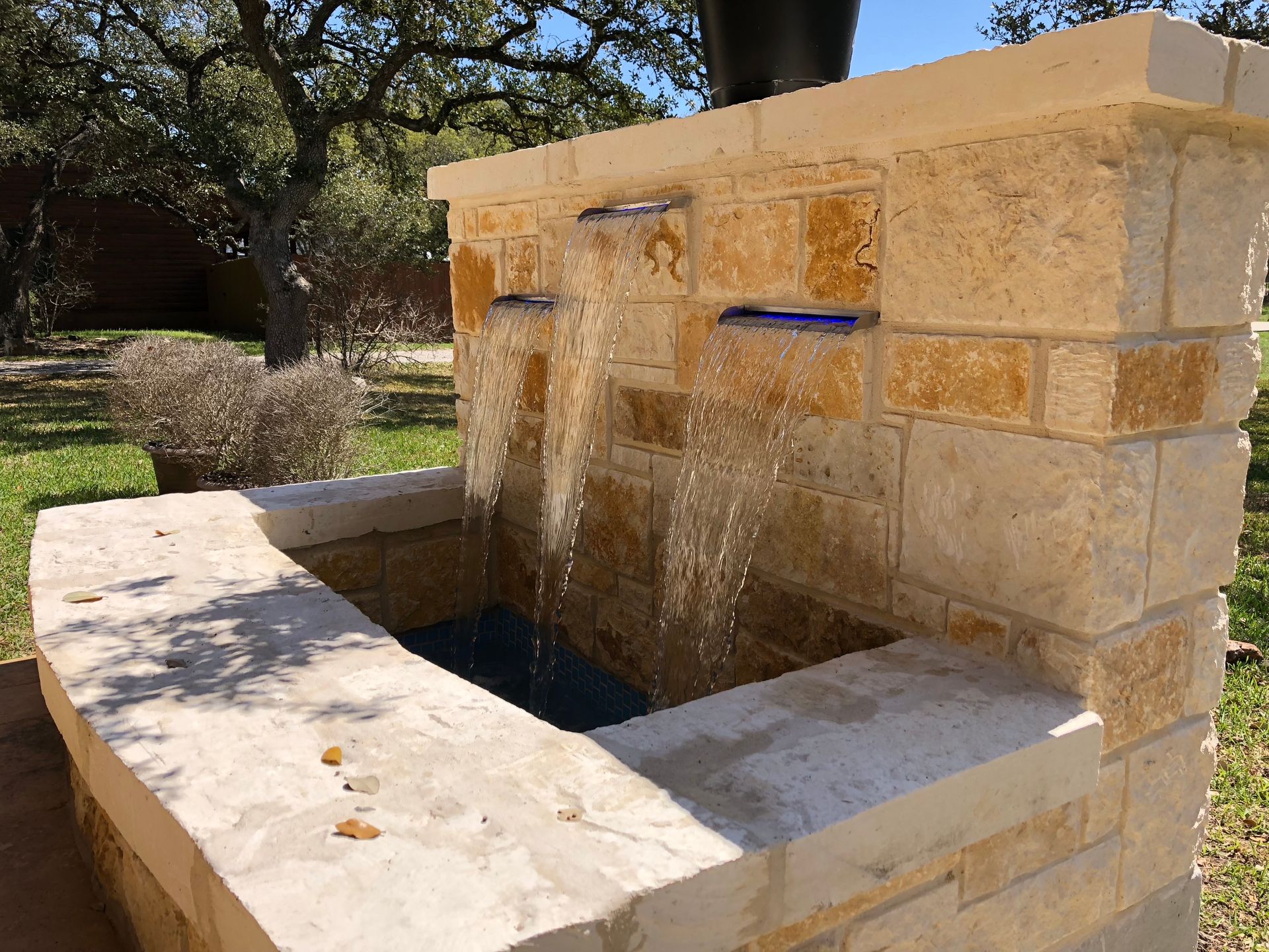 A brick wall with water coming out of it built by Fine Patio Design San Antonio TX
