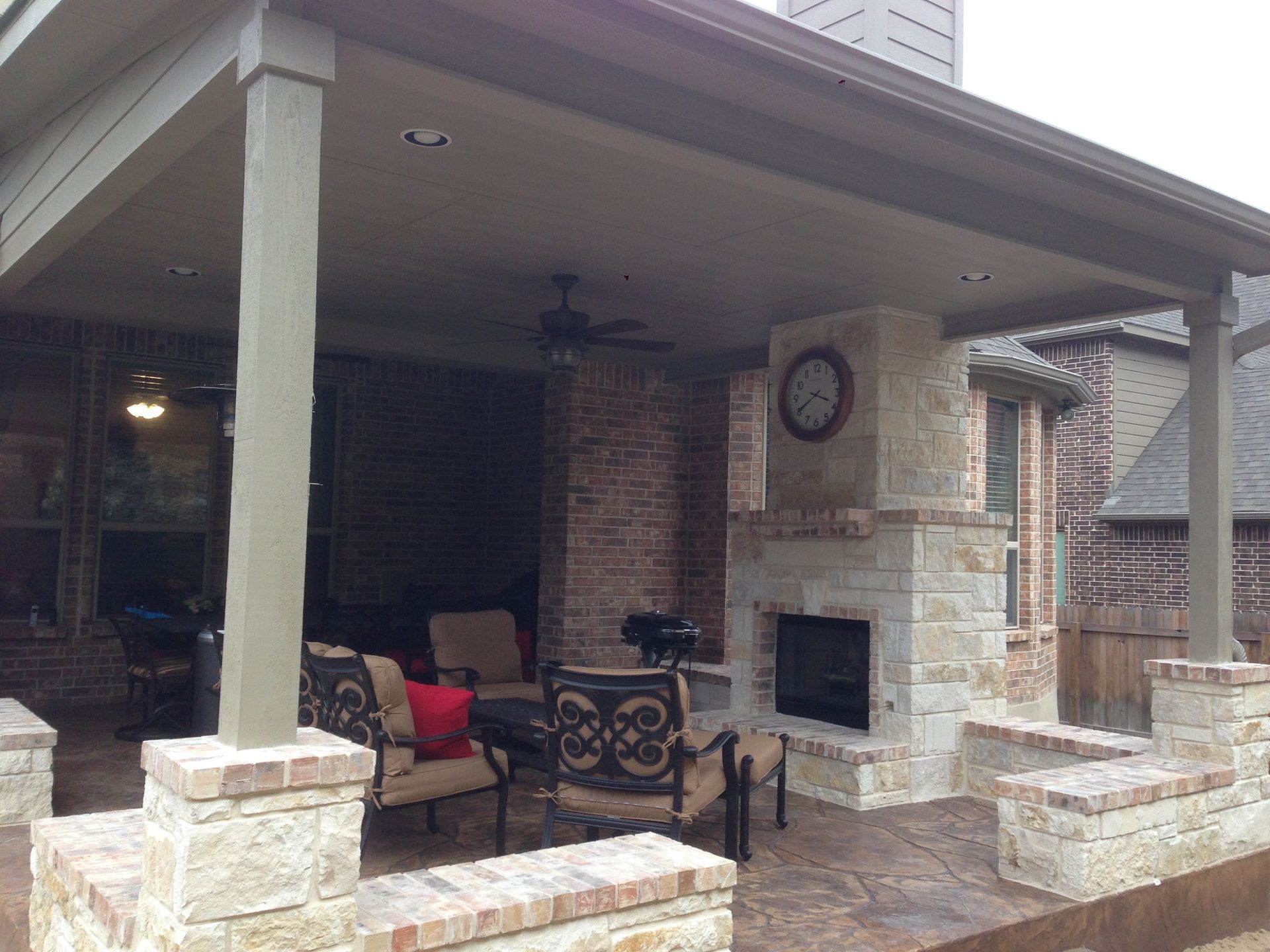 A patio with a fireplace and a clock on the wall built by Fine Patio Design San Antonio TX