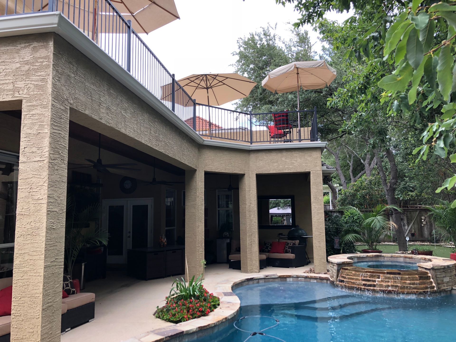 A large swimming pool with umbrellas on top of it built by Fine Patio Design San Antonio TX