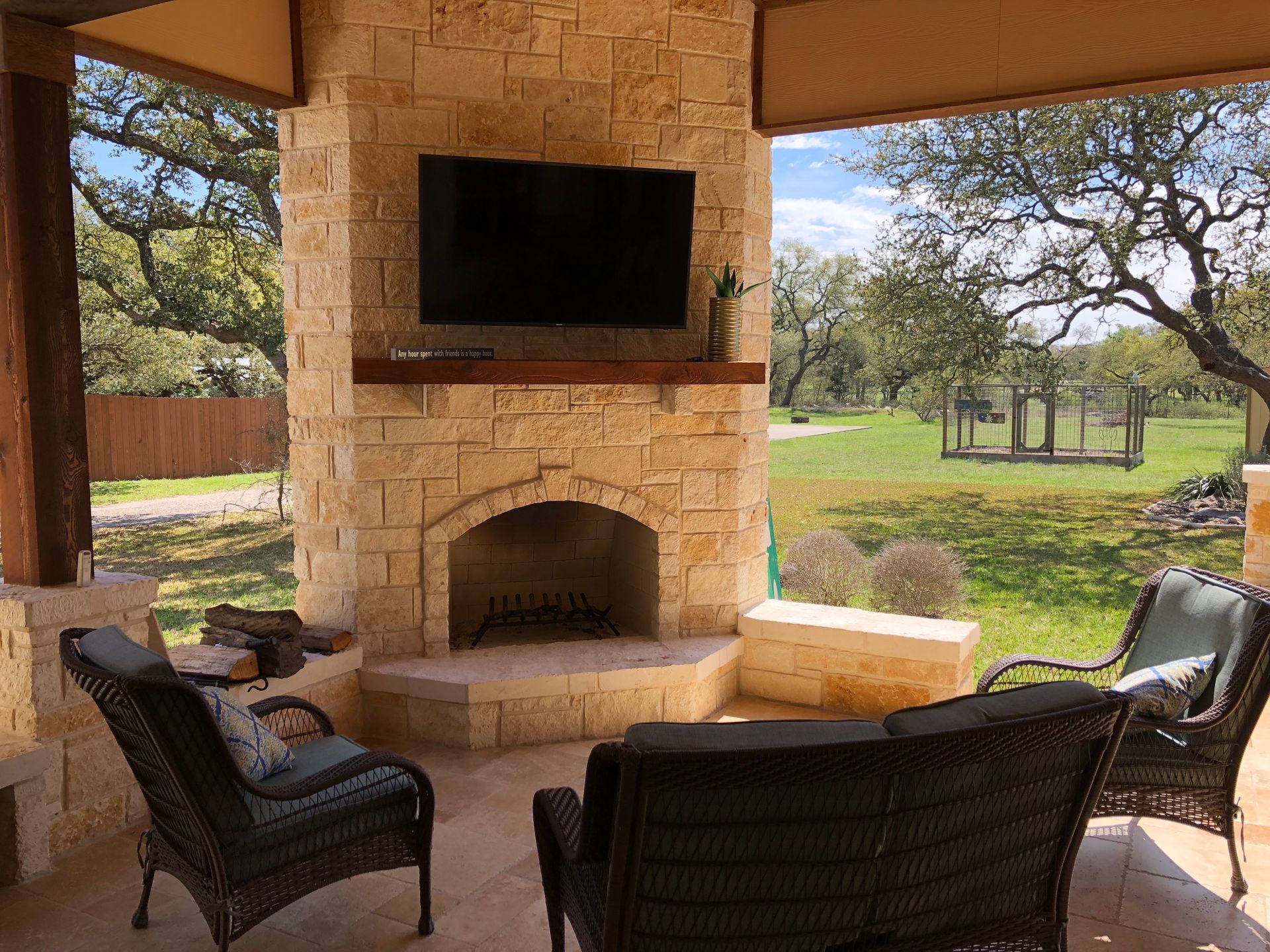 A patio with a fireplace and a flat screen tv built by Fine Patio Design San Antonio TX