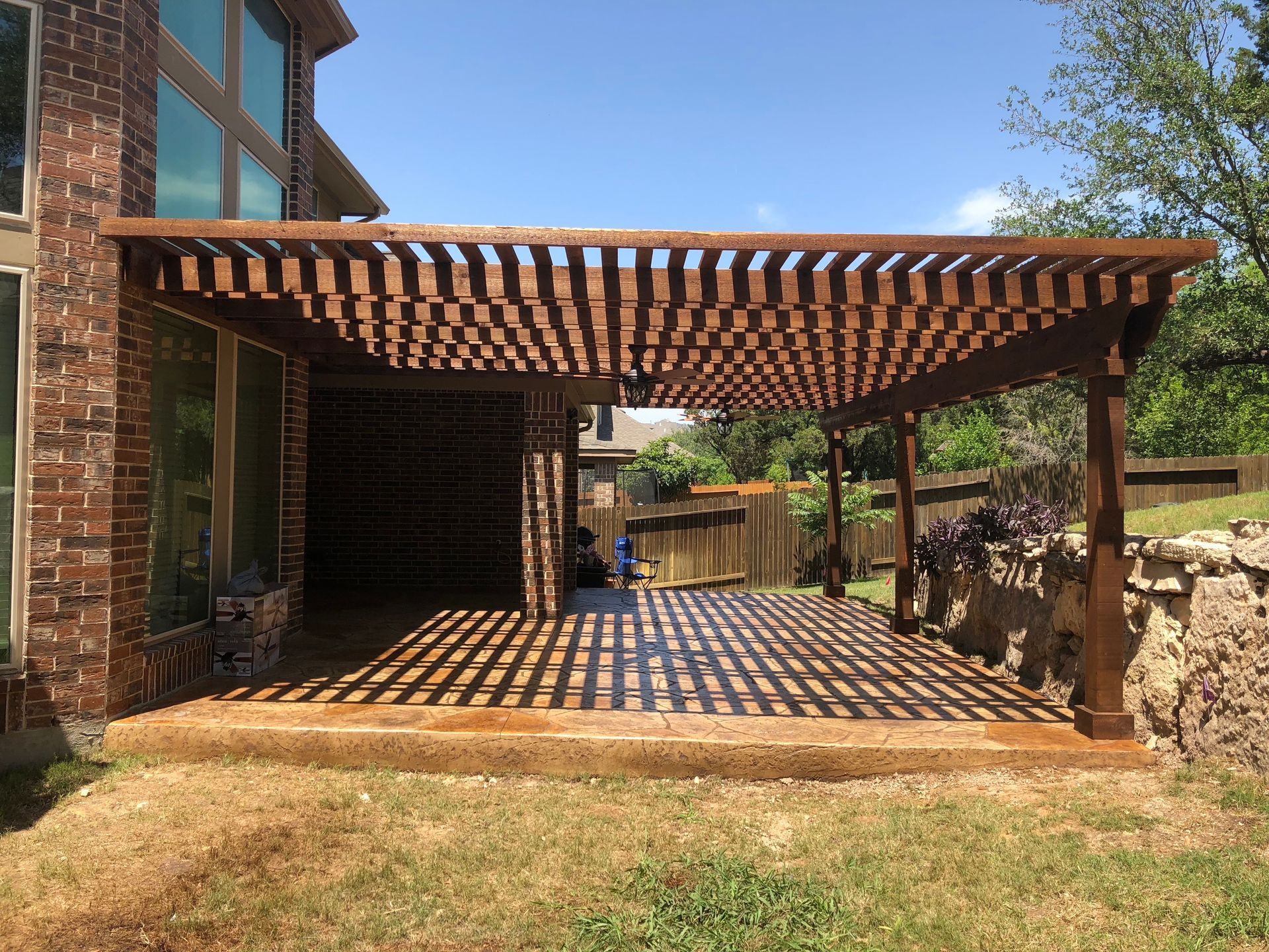 A wooden pergola in the backyard of a house built by Fine Patio Design San Antonio TX
