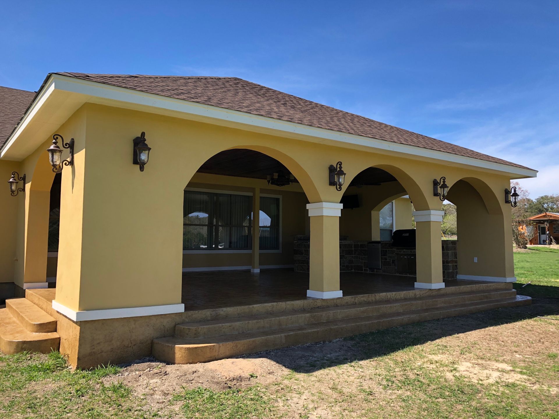 A yellow house with arches on the side of it built by Fine Patio Design San Antonio TX