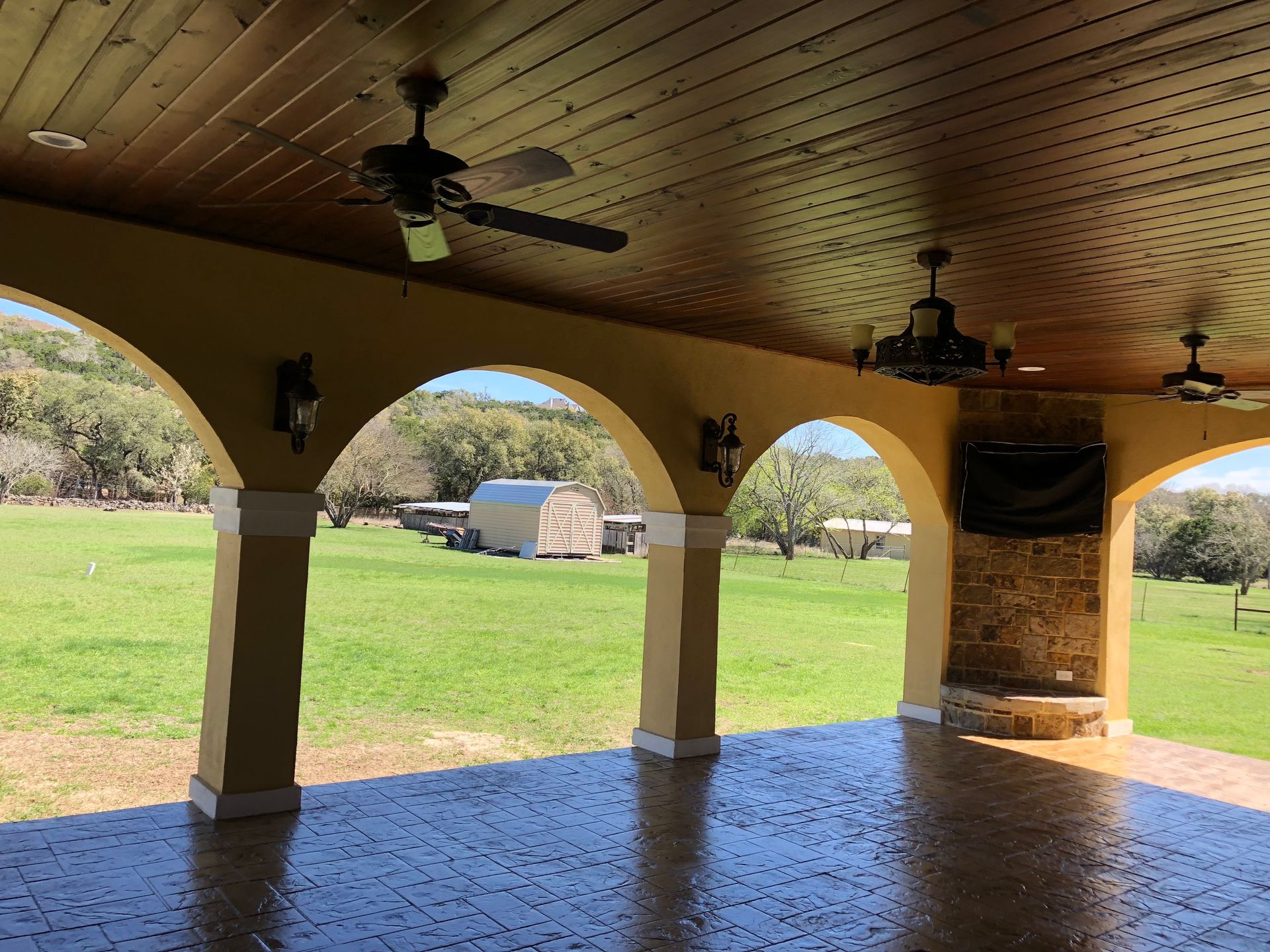 A porch with arches and a ceiling fan built by Fine Patio Design San Antonio TX