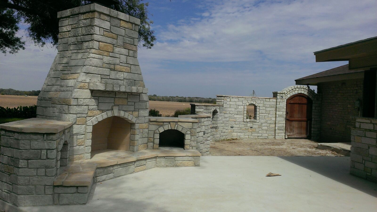 A stone fireplace sits in front of a house built by Fine Patio Design San Antonio TX