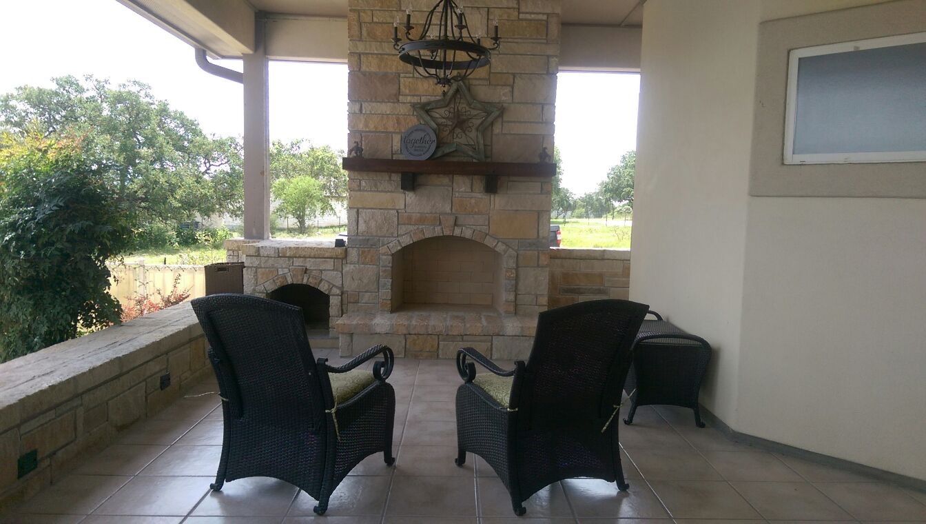 Two chairs are sitting in front of a stone fireplace built by Fine Patio Design San Antonio TX