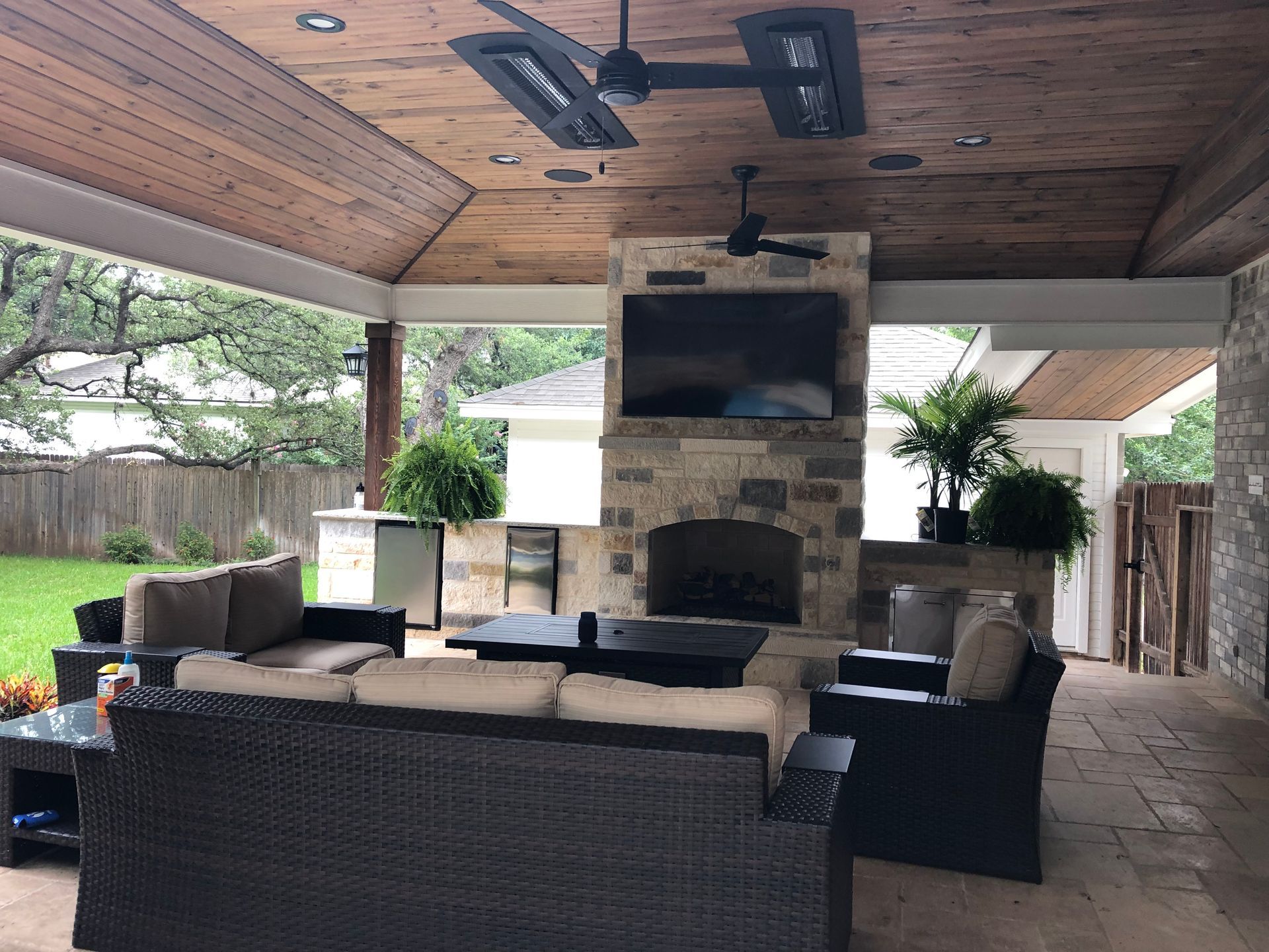 A living room with a fireplace and a ceiling fan built by Fine Patio Design San Antonio TX