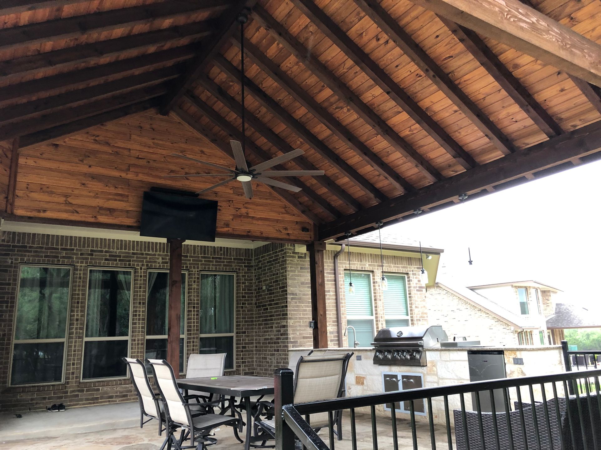 A patio with a table and chairs under a wooden roof built by Fine Patio Design San Antonio TX