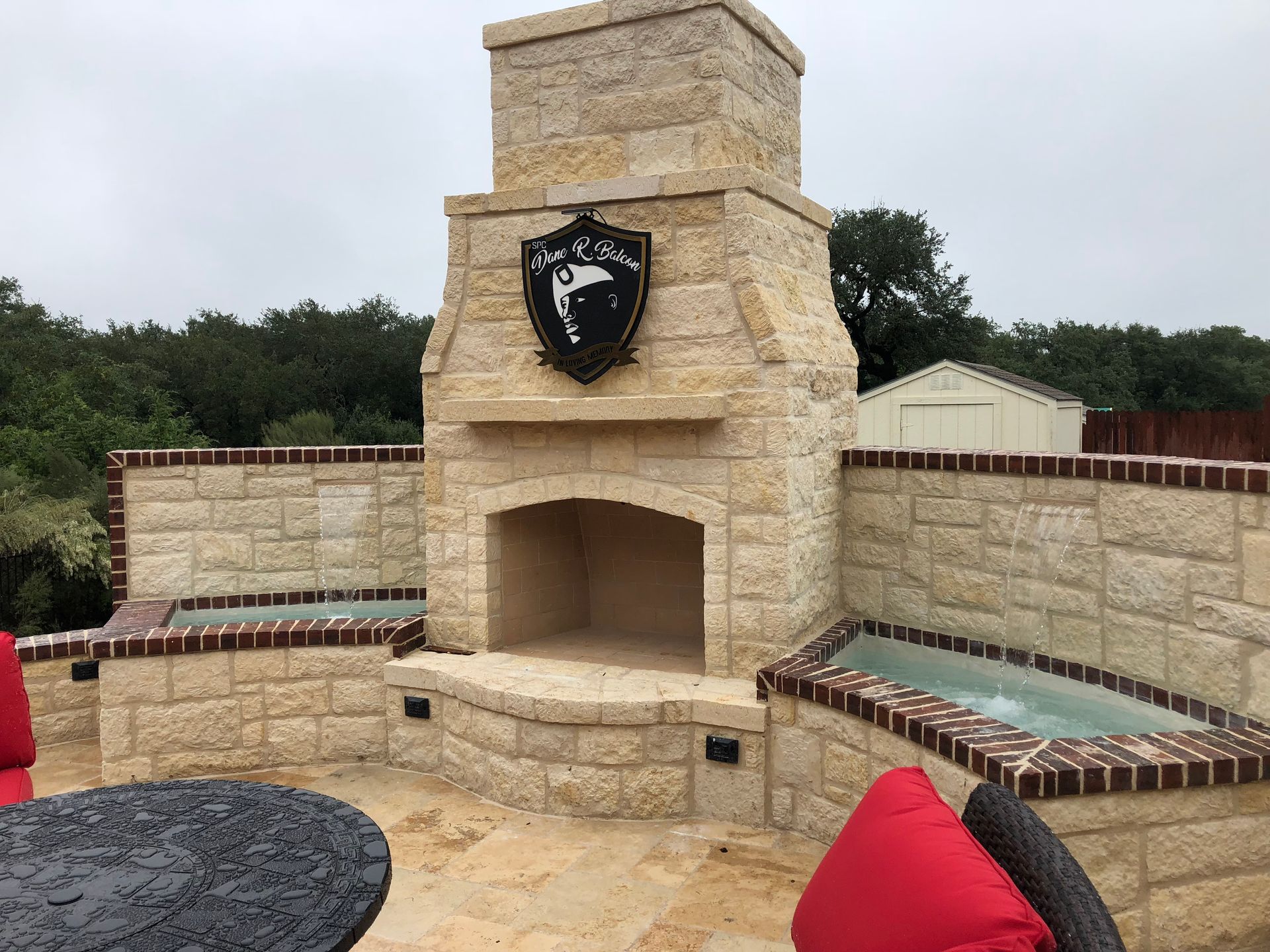 A stone fireplace with a shield on top of it built by Fine Patio Design San Antonio TX
