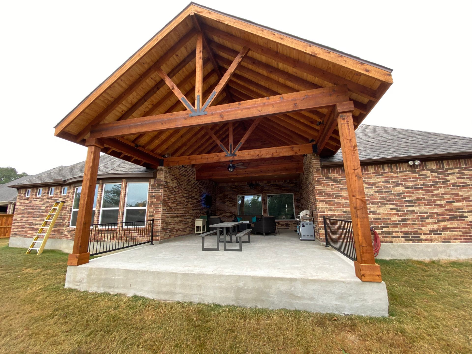 A brick house with a wooden porch and a picnic table built by Fine Patio Design San Antonio TX 