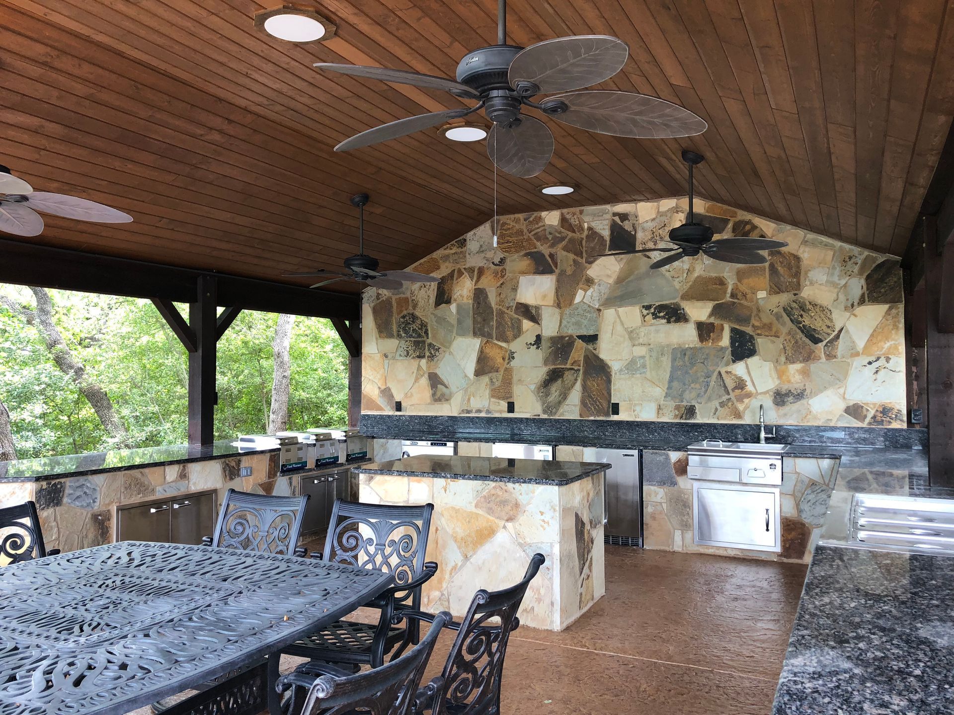 A ceiling fan is hanging from the ceiling above a table and chairs built by Fine Patio Design San Antonio TX