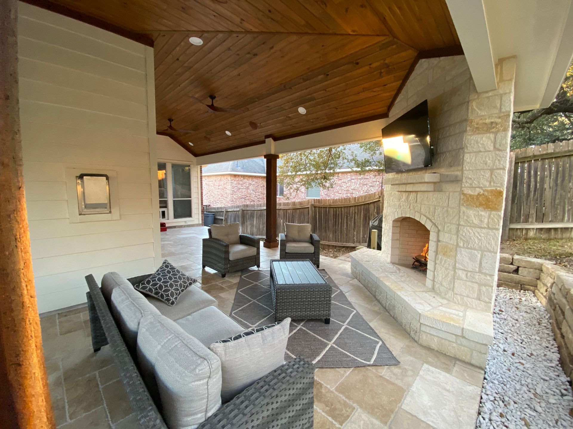 A patio with a couch and chairs and a fireplace built by Fine Patio Design San Antonio TX