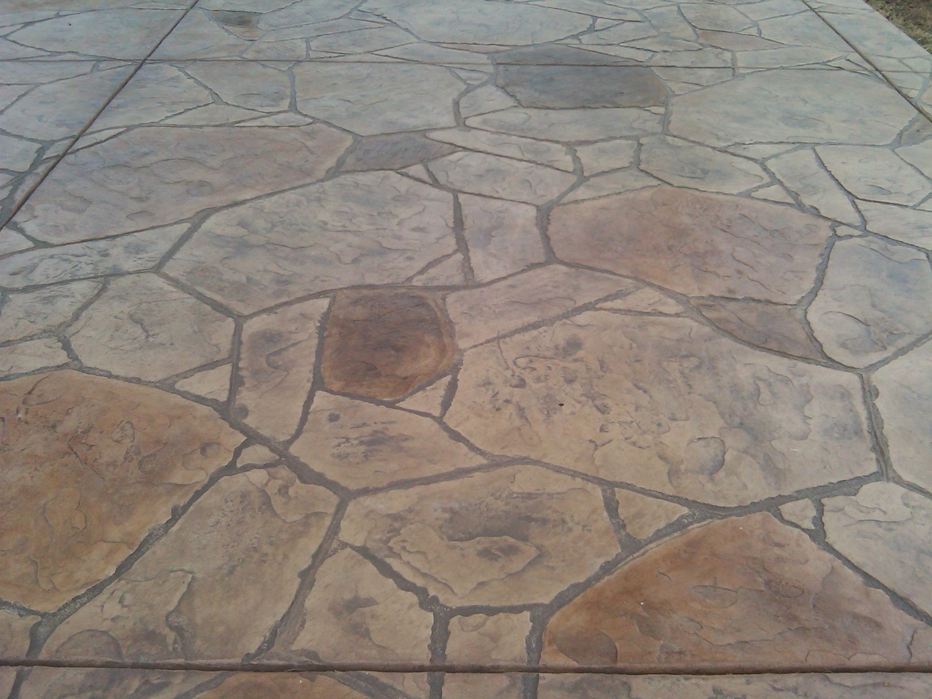 A concrete walkway with a pattern of rocks on it built by Fine Patio Design San Antonio TX