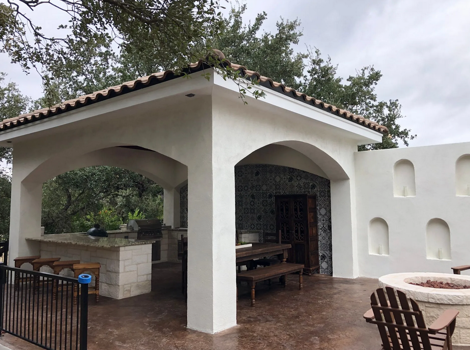 A white building with arches and a fire pit built by Fine Patio Design San Antonio TX