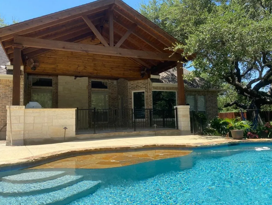 A large swimming pool with a house in the background built by Fine Patio Design San Antonio TX