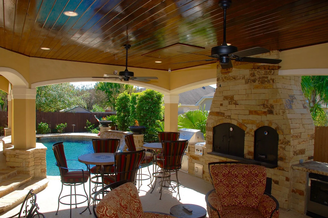 A patio area with a ceiling fan and a fireplace built by Fine Patio Design San Antonio TX