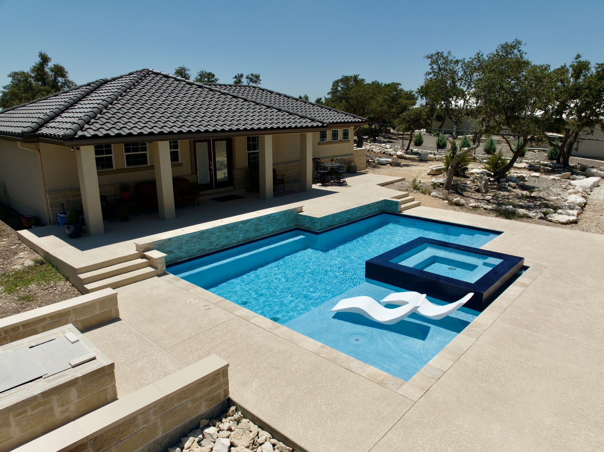 A house with a large swimming pool in front of it built by Fine Patio Design San Antonio TX
