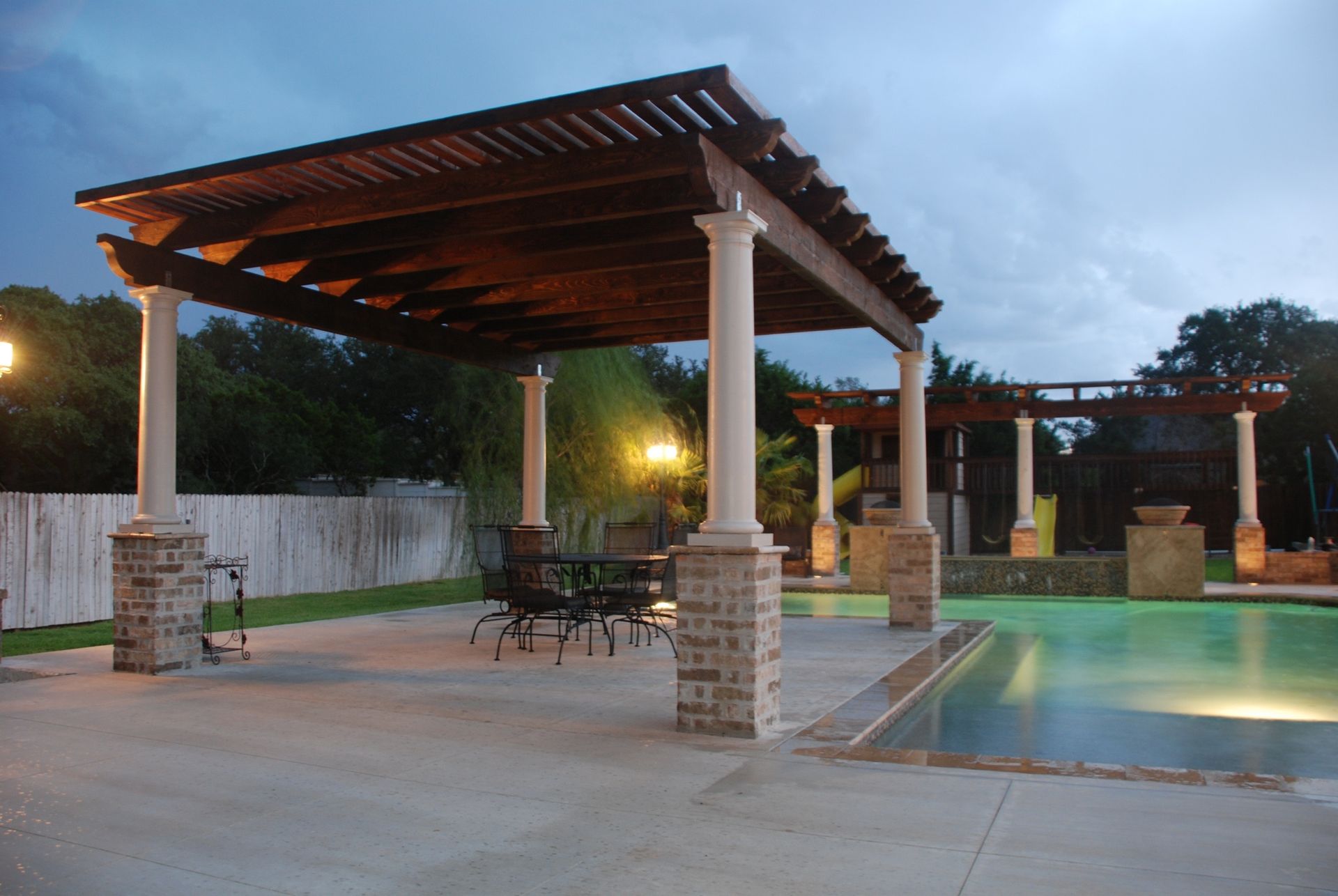 A patio area with a pergola and a swimming pool built by Fine Patio Design San Antonio TX