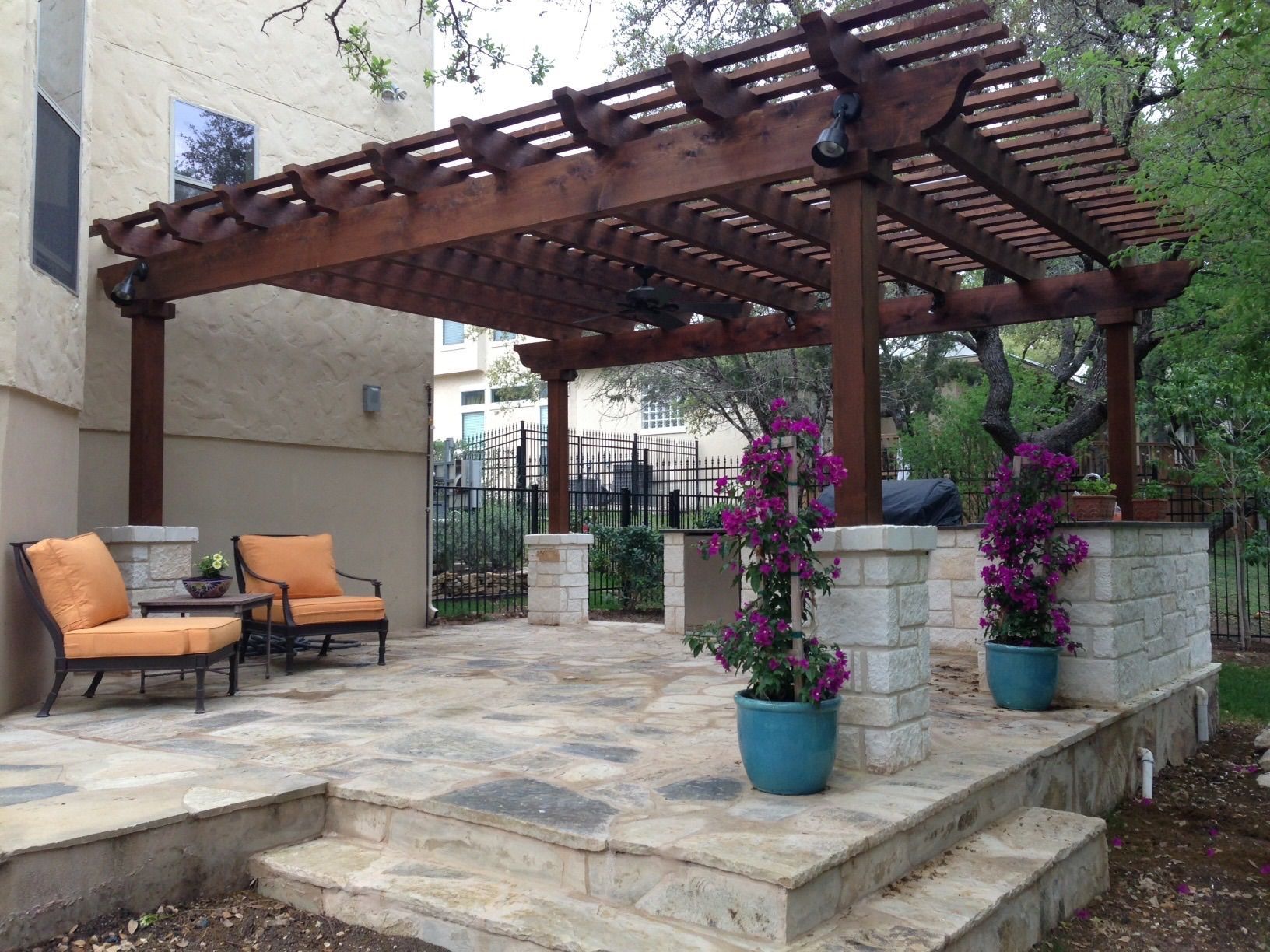 A patio with a pergola and purple flowers built by Fine Patio Design San Antonio TX