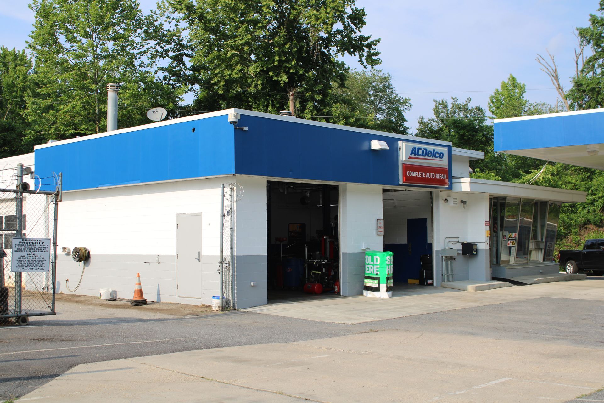 Auto repair shop with blue and white facade and open garage door. | Fort Meade Auto Center