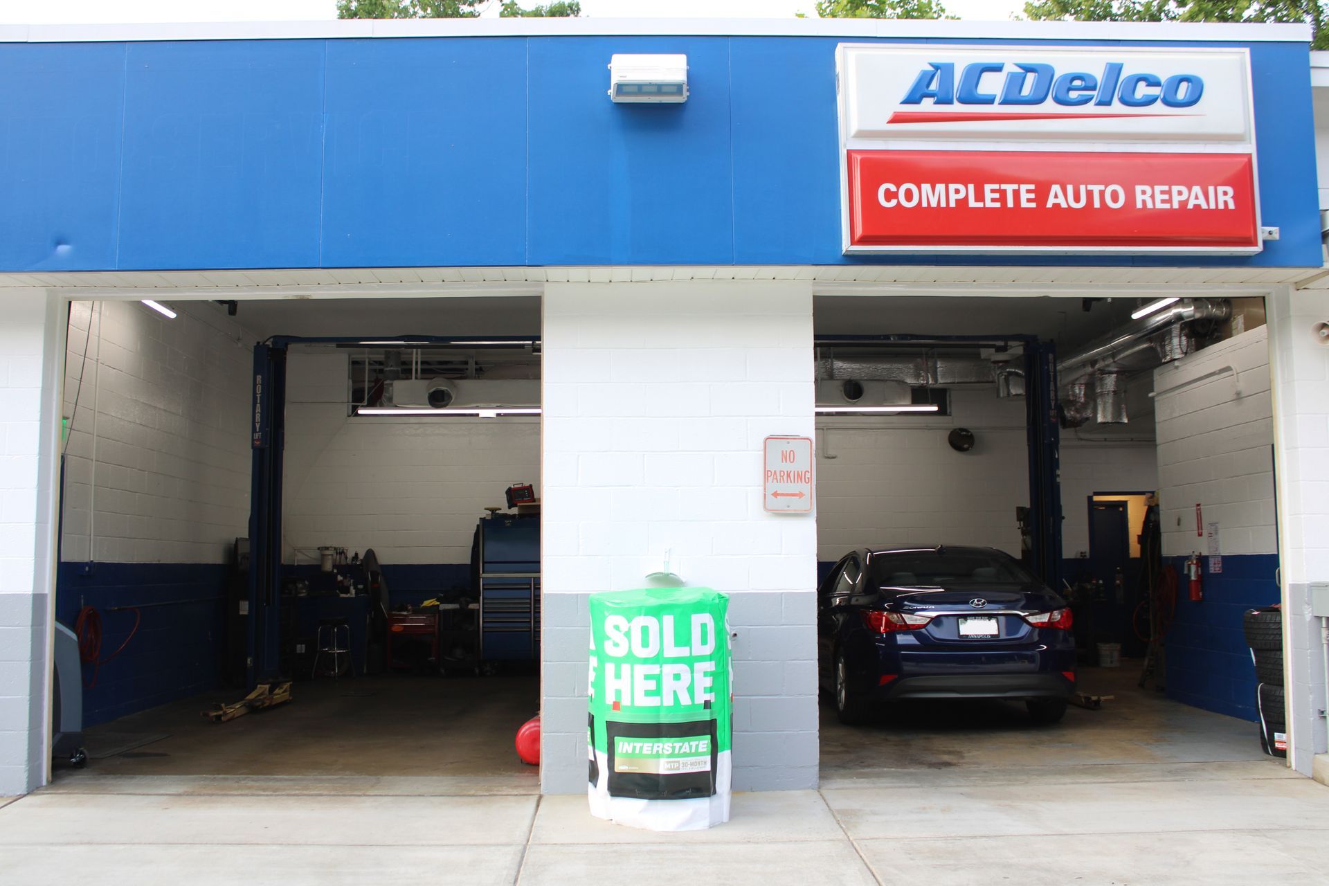 ACDelco auto repair shop exterior. Blue, red, and white building with two open bays. A car is in one bay. | Fort Meade Auto Center