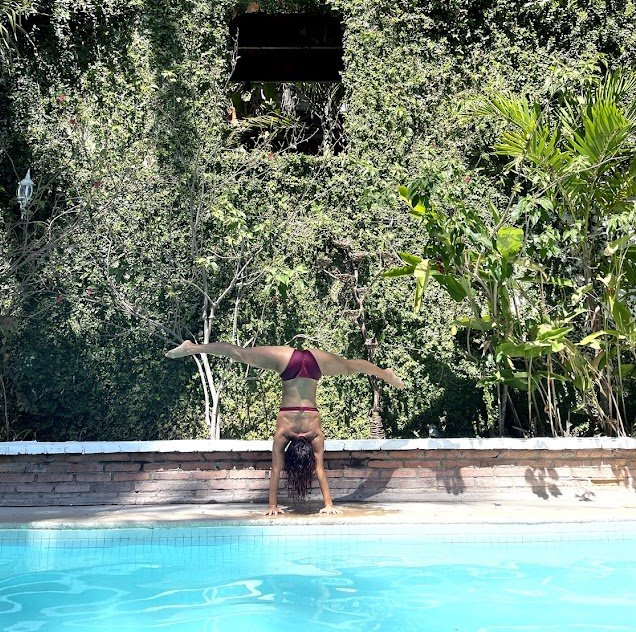 A woman is doing a handstand in a pool
