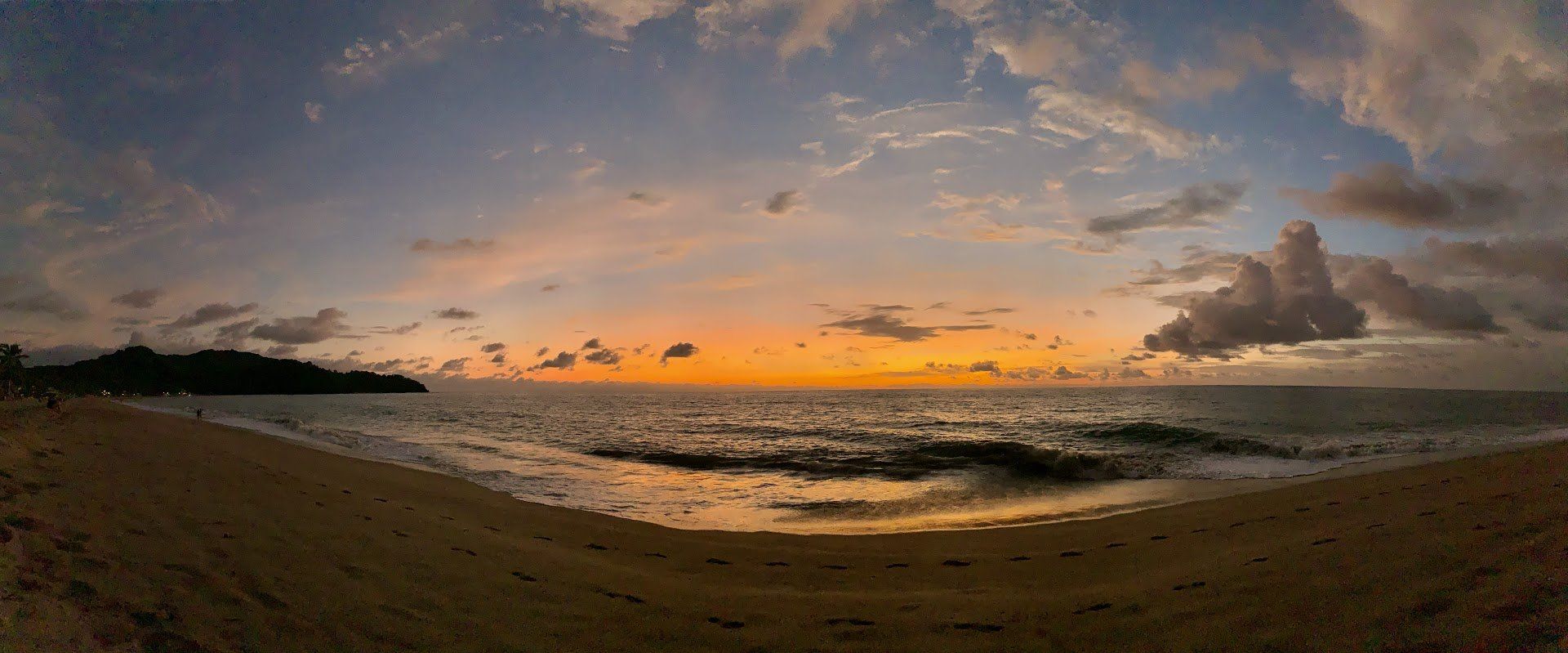 Una vista panorámica de una playa al atardecer.