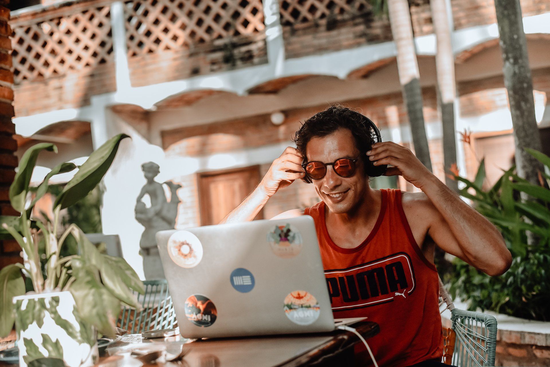 Un hombre que lleva auriculares está sentado en una mesa con una computadora portátil.