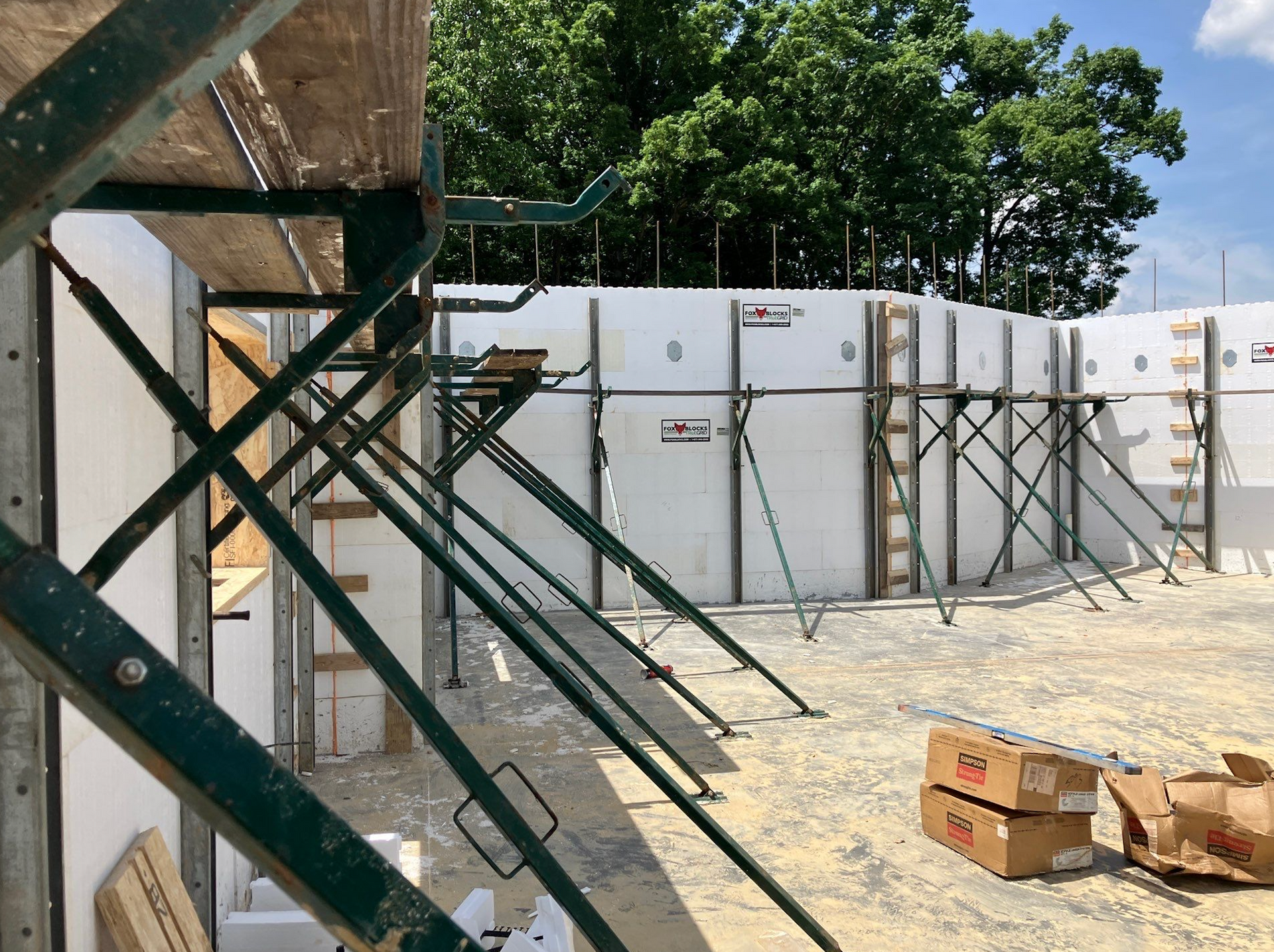 Outdoor construction site with green metal stairs, concrete barriers, and stacked boxes in the dirt