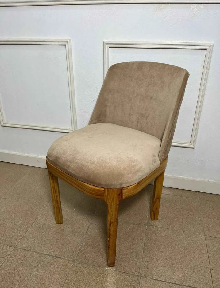 Tres sillas de comedor tapizadas con patas de madera alineadas sobre un suelo de baldosas, una silla verde oscuro delante.