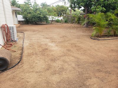 A backyard with a lot of dirt and a house in the background.