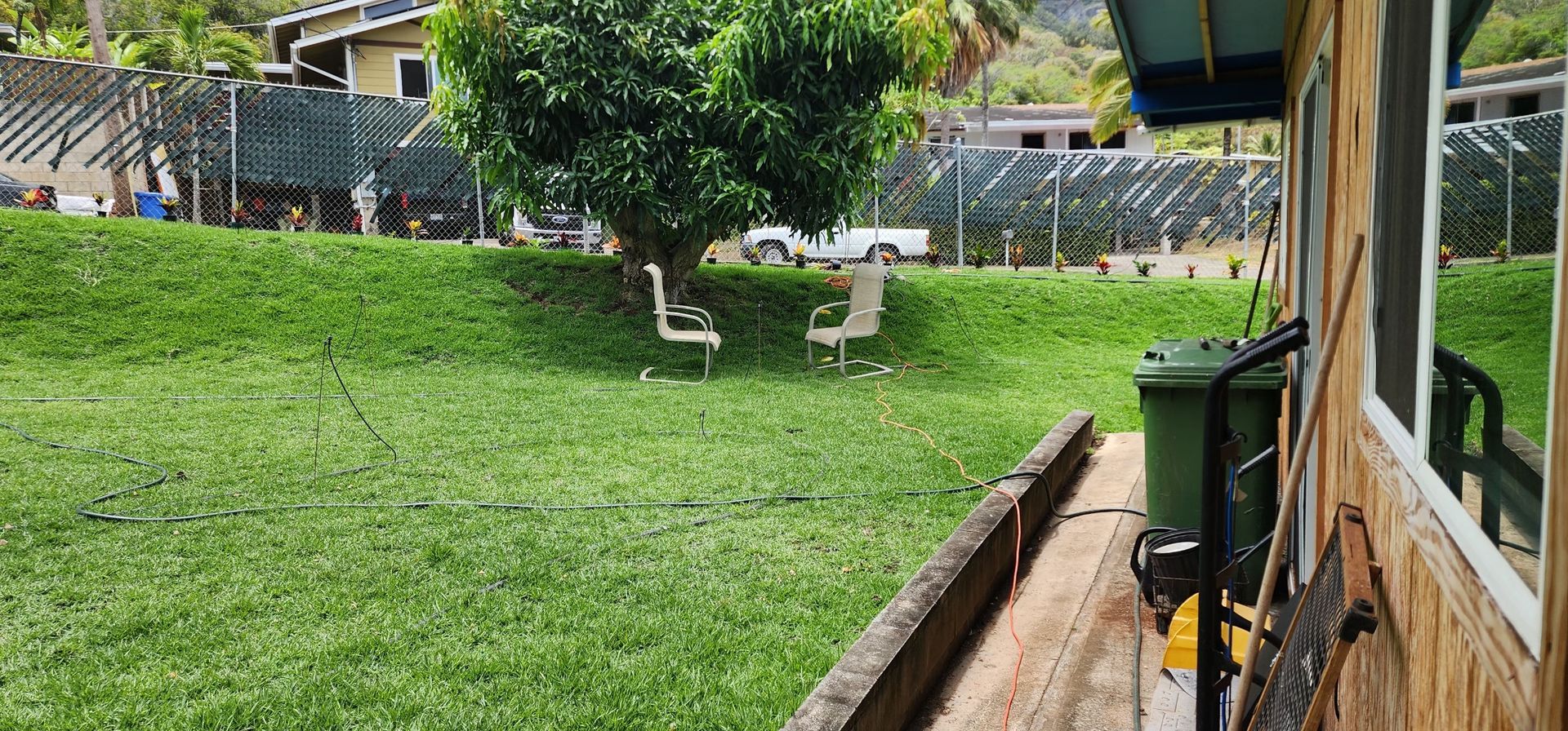 residential backyard with green lawn and two lawn chairs