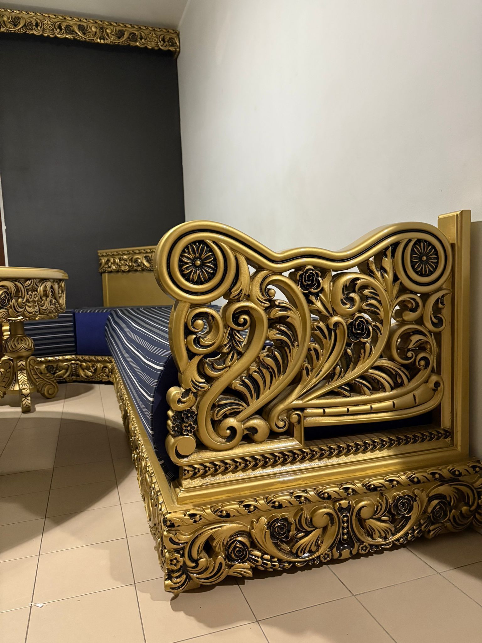 In una stanza c'è un letto dorato con un materasso blu.