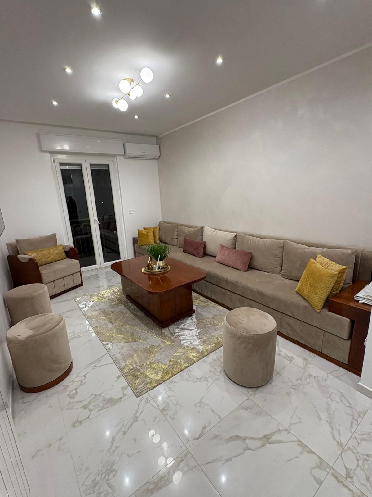 Un soggiorno con divano, sedie, pouf e tavolino.