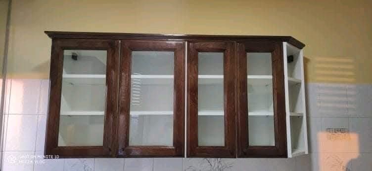 Un mobile da cucina con ante in vetro e ripiani è appeso alla parete.