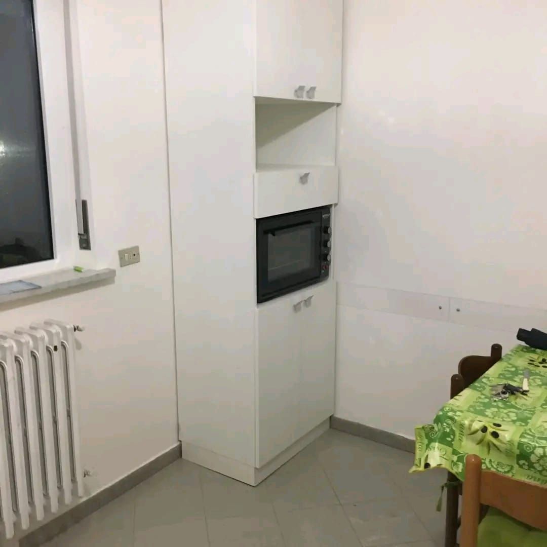 Una cucina con tavolo, sedie e forno a microonde.