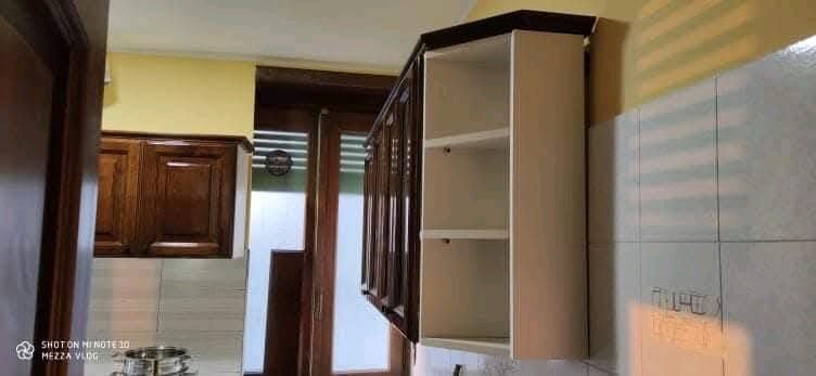 Una cucina con mobili in legno e ripiani bianchi.