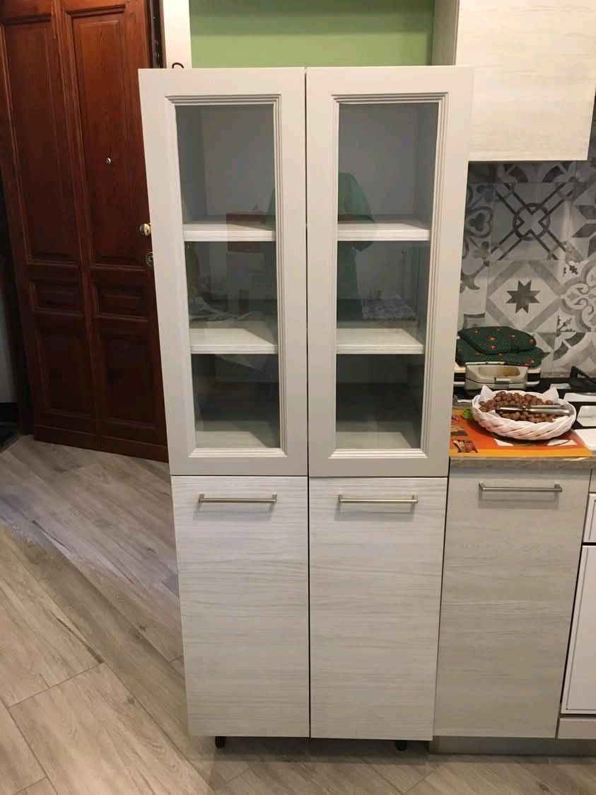 In cucina c'è un mobile bianco con ante in vetro.