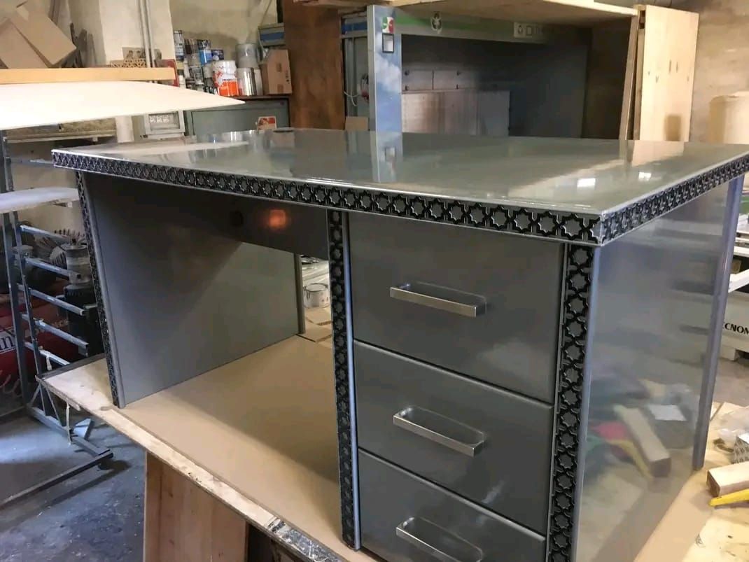 Una scrivania di metallo con tre cassetti è appoggiata su un tavolo di legno.