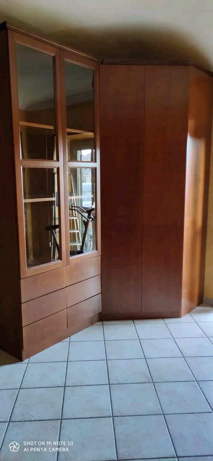 Una stanza con un armadio in legno e un pavimento piastrellato.