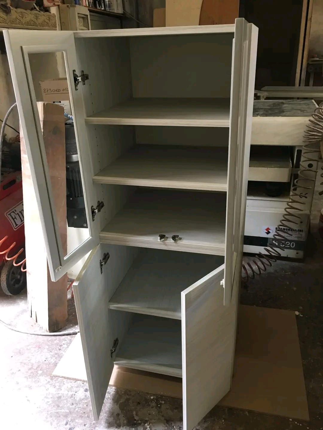 Un mobile bianco con le ante aperte e i ripiani.