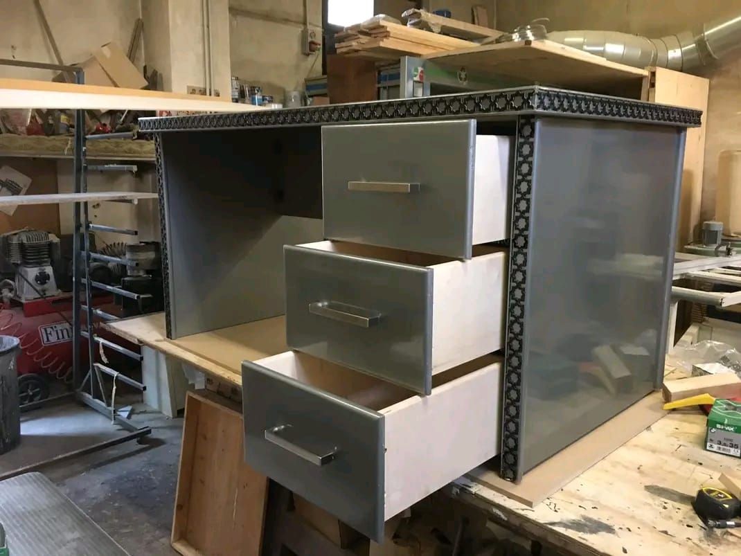 Una scrivania di metallo con tre cassetti aperta in un'officina.